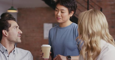 Woman team leader meeting with diverse group of startup business people pointing at computer screen in trendy modern office with red brick walls slow motion