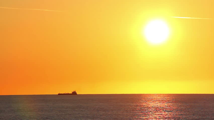 A freighter ship on the ocean during a sunset.