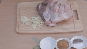 EDIT MULTICAM VIDEO Piercing thick piece of pork with broad knife for further marinating with garlic. There are three bay leaves on table in front of chopping board and three bowls. 
