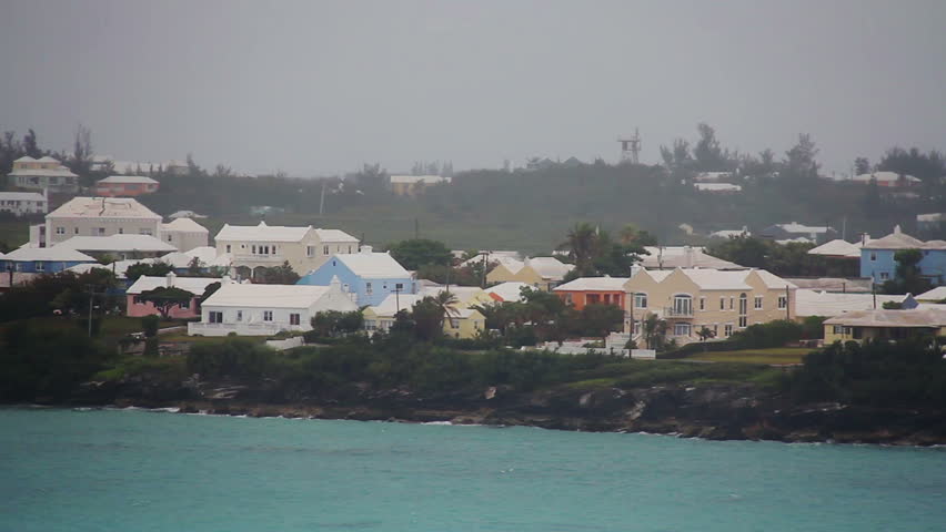 Sailing past the shoreline of the island of Bermuda on a cloudy day.