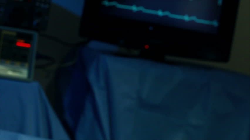 Close up of action as a surgical tool is handed to a surgeon in an operating room setting with out of focus blinking lights in the background. | Shutterstock HD Video #1271236