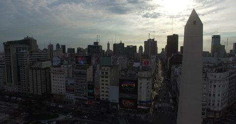 Aerial Drone scene of Obelisk in Buenos Aires, Argentina, at sunrise in the morning. 9 de Julio main Avenue, 9 of july. Traffic and people going to work. Camera vertical panning.