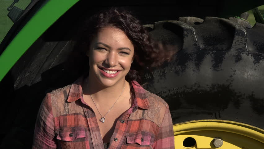 Portrait of a young woman in front of a tractor tire