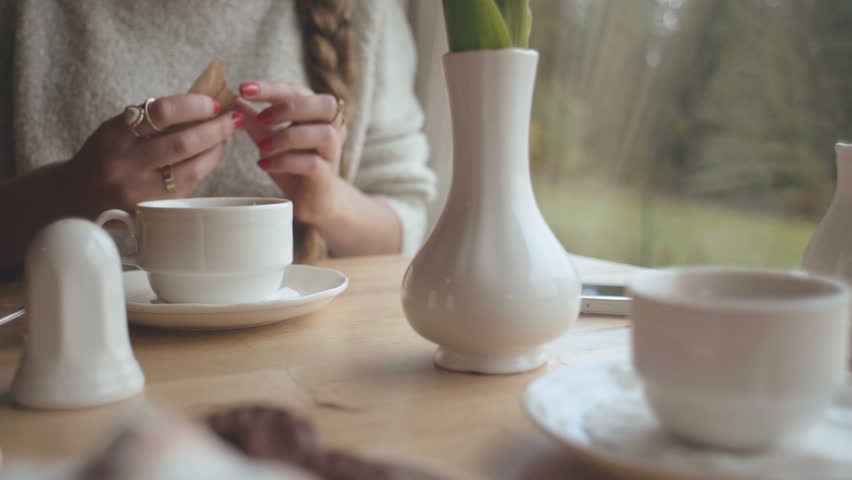 Close up hands of young woman having morning coffee at home.