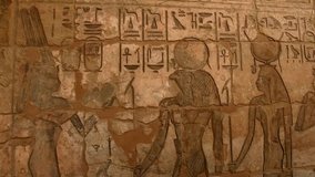 Ancient Egyptian hieroglyphic carvings on a temple wall at Medinat Habu in Luxor
