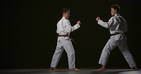Two boys performing Ju-jitsu duo system competition exercise slow motion 50fps on black background