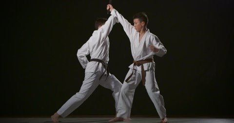 Two boys performing Ju-jitsu duo system competition exercise slow motion 50fps on black background