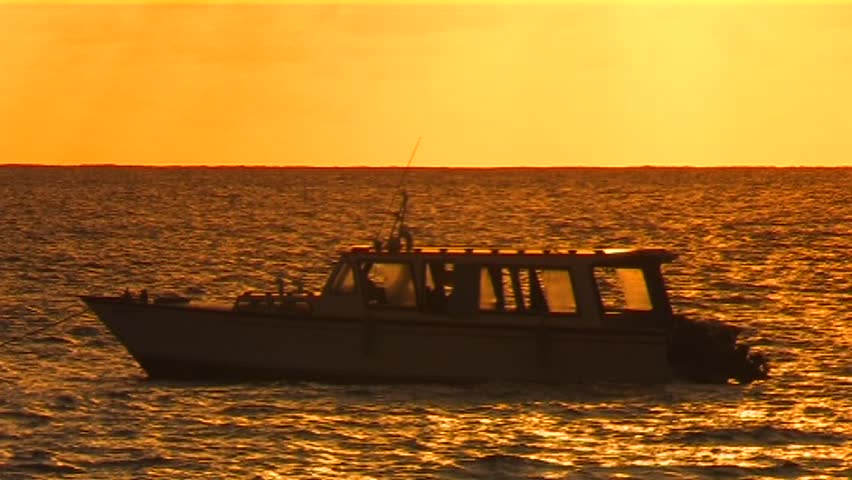 A boat floating in the sunset 