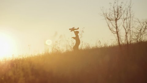 Boy with the airplane in the hands of running on a hill at sunset