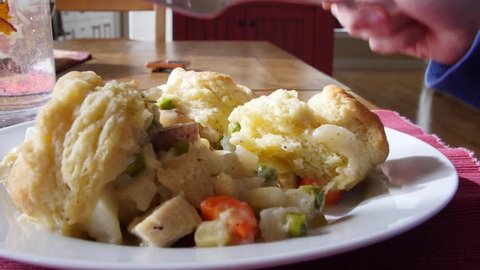 A family eats chickent pot pie made with biscuits at the dinner table