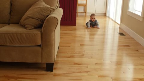An adorable little boy learns to scoot around on his bum using his hands and feet