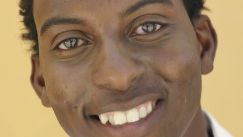 Portrait of african american college student smiling and looking at camera with yellow wall in background. Young happy black man and feelings Video stock