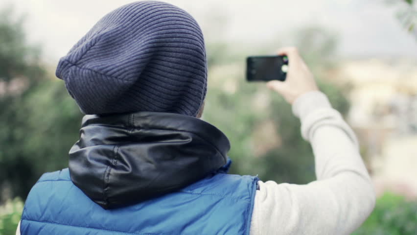 Man taking photo in park with cellphone, slow motion shot at 120fps 
