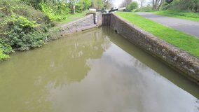 Aerial footage moving along a small canal and over a canal lock