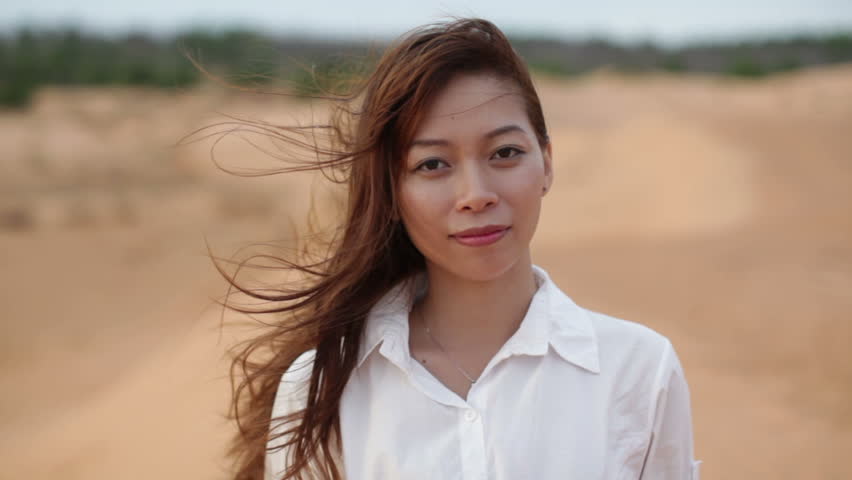 Asian woman smile outdoor desert wind blowing hair, wear white shirt close up face of young happy girl looking to camera cheerful