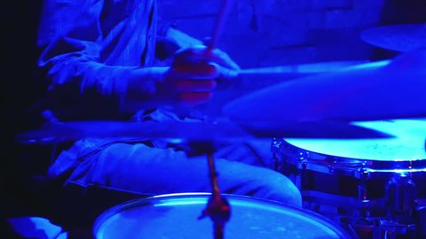 SLOW MOTION: Macro view of drummer's hands during rock show. Rack focus.