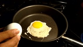 Slow motion clip of cracking a frying an egg on a pan.
