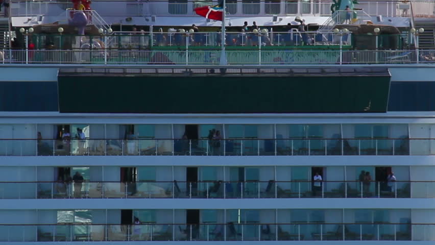 People wave as a cruise liner leaves dock.