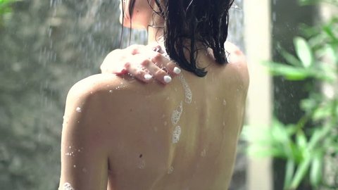 Young naked woman washing sexy body under shower, super slow motion
