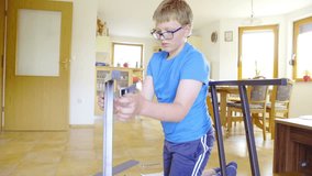 Screwing sliding rail on table iron frame 4K. Boy in blue shirt putting together a table for computer, adding a sliding rail on one side of iron frame. Shoot in living room with kitchen in background. - Powered by Shutterstock - Get 15% off with code: PIKWIZARD15