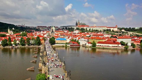 PRAGUE, CZECH REPUBLIC - JULY 30, 2013: Above view at The Charles Bridge crowded with tourists over Vltava river and old district buildings in distance.
