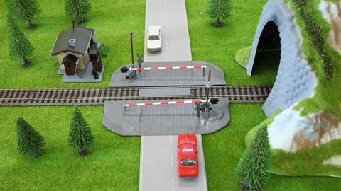Model of train enters a tunnel, the cars passed him on crossing. Stop motion.