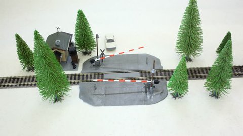 The model of the railway crossing: moving cars and trains around the trees. Stop motion.