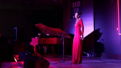 MOSCOW, RUSSIA - OCTOBER 30, 2015: Woman in red dress sings on a stage during "RED TIE" National Award for corporate event management industry. Swissotel Red Hills.