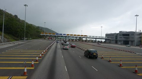 Pass inoperative toll road gate, no need to pay here sign. Lantau island, Route 8 roadway, highway to Hong Kong International Airport. Empty road, early morning time, cloudy sky and mountains scenery.
