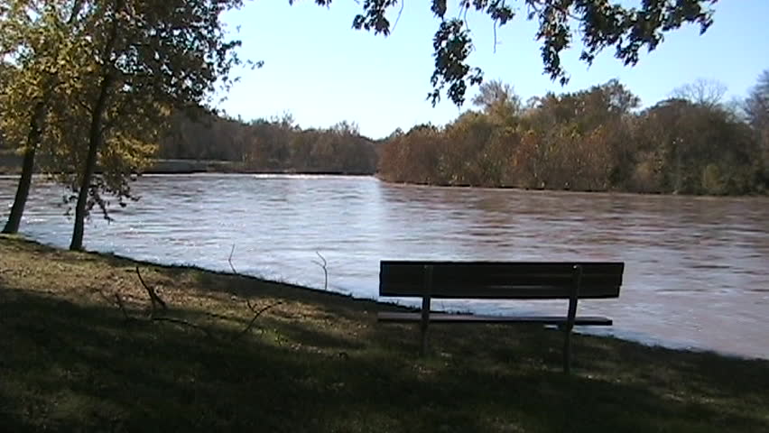 Empty park bench by flowing river