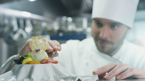 Happy professional chef in a commercial kitchen is garnishing ice cream dessert with strawberry. Shot on RED Cinema Camera in 4K (UHD).