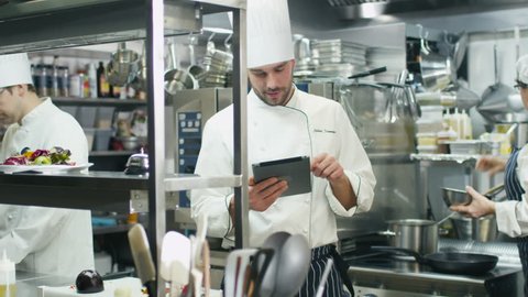 Professional chef in a commercial kitchen in a restaurant or hotel is using a tablet computer. Shot on RED Cinema Camera in 4K (UHD).