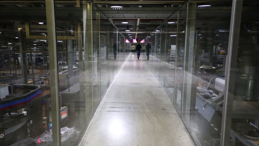 Glass hallway with going man in modern brewery factory. Text on glass: medical office, office 325, pretrip inspection of drivers