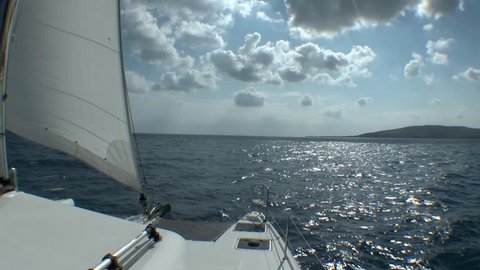 Approaching sailing catamaran to the island on the horizon.
