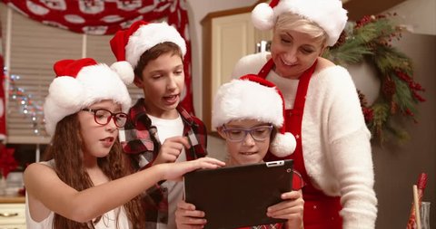Happy family browsing on a tablet in christmas hats