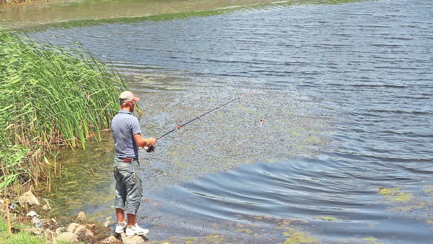 Back view of fisherman casting the line into pond 