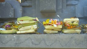 Offerings of money. flowers and incense to Hindu gods. presented on a long. cement altar at Tirta Empul Temple in Bali. Indonesia. Video UltraHD