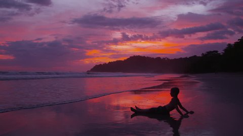 Cinemagraph - Young boy sitting on beach at sunset, Costa Rica. Looping Motion Photo.  Stock Video
