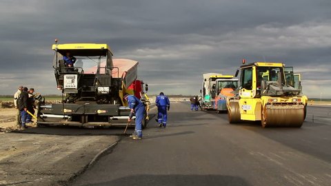 TULCEA, ROMANIA - NOVEMBER 08: Tracked paver laying fresh asphalt pavement on a runway as part of the Danube Delta international airport, time lapse on November 08, 2015 in Tulcea, Romania.