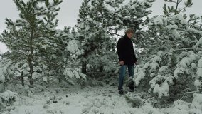 Young man is singing with emotions with trees covered with snow on winter forest background.