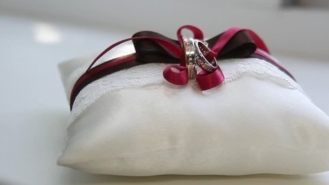 Red wedding pillow for rings and present bow decorated on candles and gifts on white background