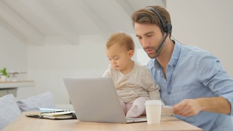 Busy businessman working from home and watching baby 