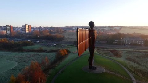 Drone / aerial shot flying around the side revealing the front of the Angel Of The North in the North of England with traffic driving down surrounding roads. Shot September 2014.