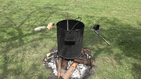 resin boiling an old dirty pot on fire outside on meadow. 4K UHD video clip.