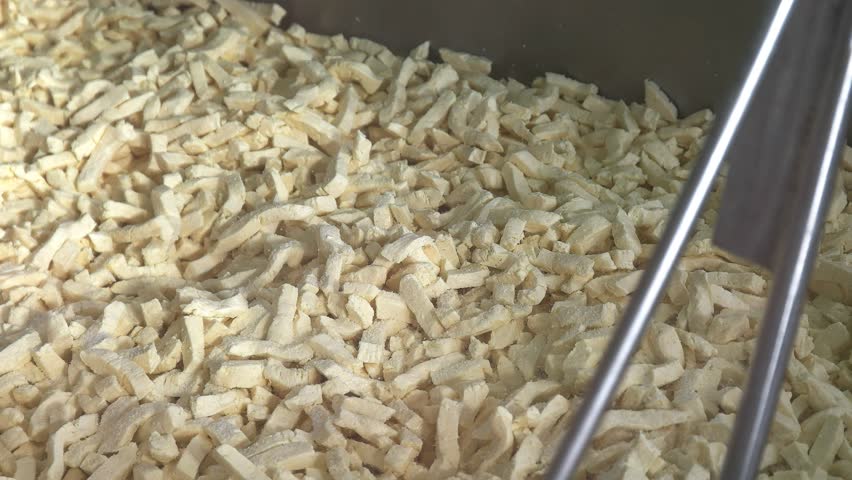 a worker adds salt to fresh cheese curd at a boutique cheese factory