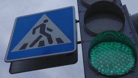 Ungraded: Traffic lights with pedestrian crossing sign. Red, yellow and green lights. Blinking light against sky background. Source: Canon EOS, ungraded H.264 from camera. (av13142u)