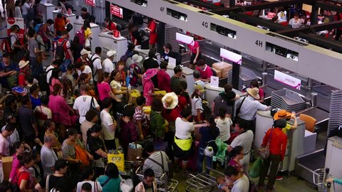 BANGKOK - MARCH 30, 2015: Overcrowded check-in counters, unidentified chinese passengers throng around, Don Mueang, DMG, old international airport. Camera located above, high angle view from top