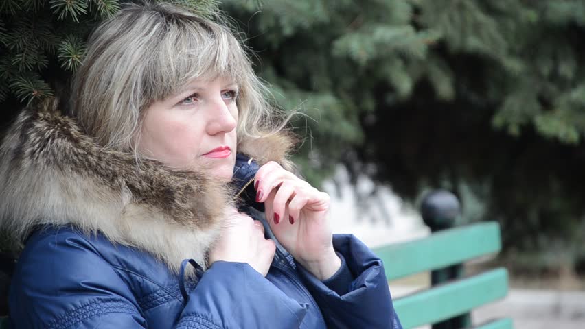 A woman alone sitting on a bench near the fir