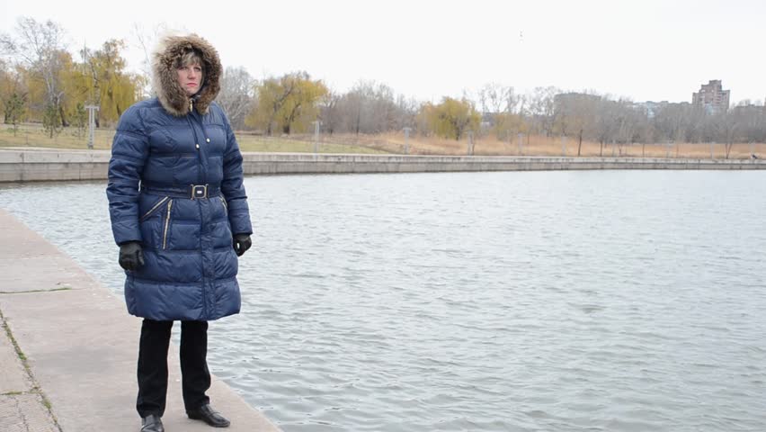 Woman in jacket with hood on the river bank