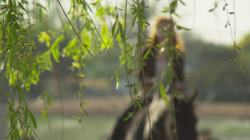 Blur in to young woman riding horse through ranch farm